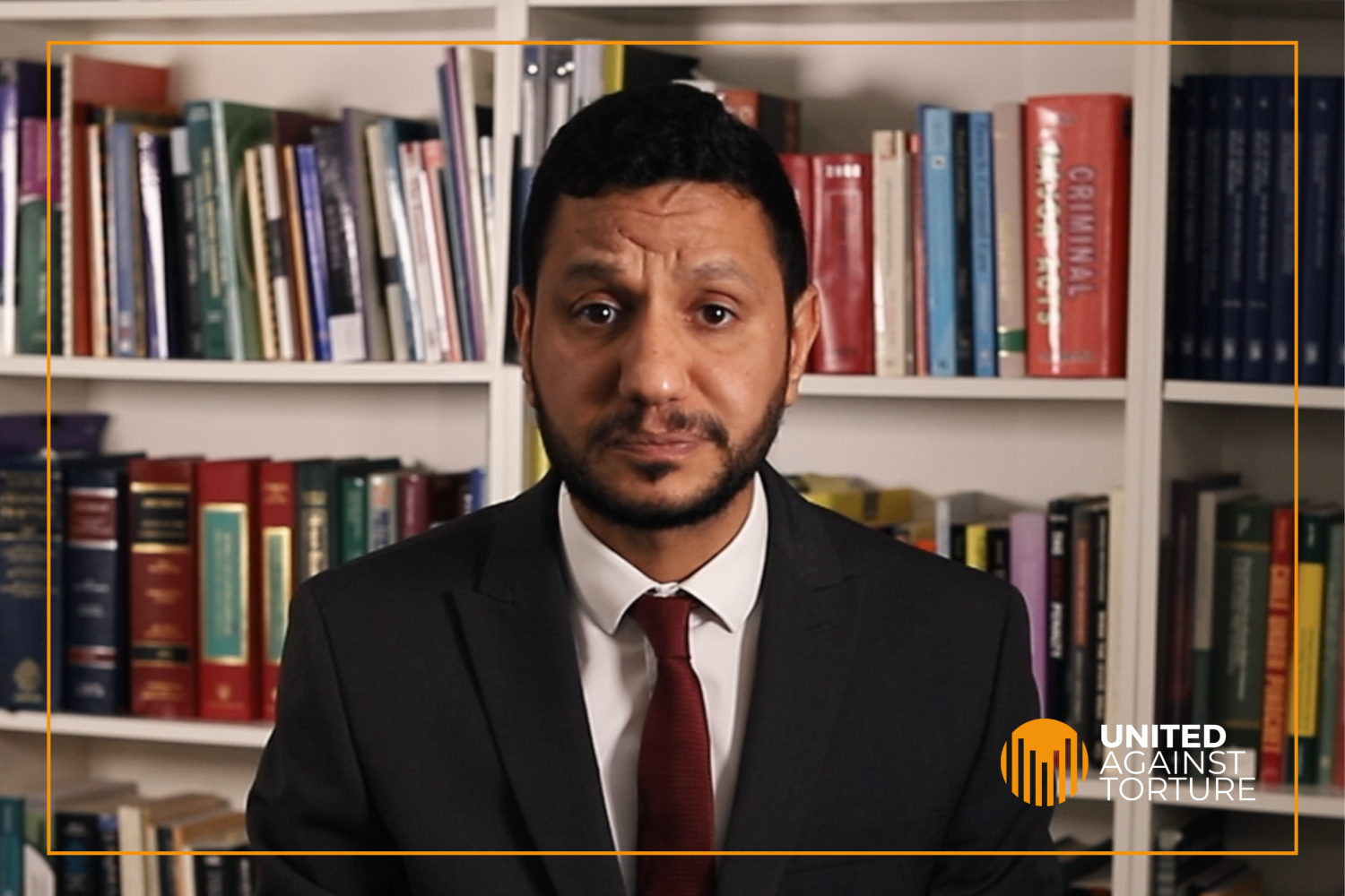 Sayed Alwadaei in a suit and tie, sat in front of a bookcase.